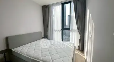 Bright bedroom with large window and modern decor in urban apartment.