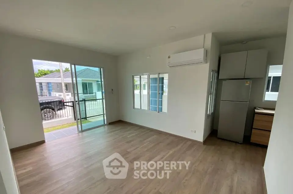 Spacious modern living room with large windows and balcony access in a contemporary home.