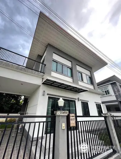 Modern two-story house with sleek design and spacious balcony in suburban neighborhood.