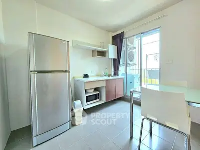Modern kitchen with stainless steel fridge and microwave, featuring open layout and balcony access.