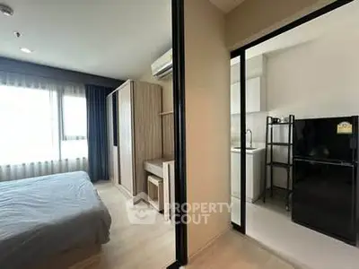 Modern apartment with bedroom and compact kitchen, featuring sleek design and natural light.