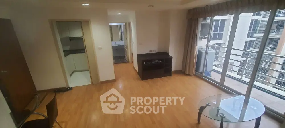 Spacious living room with gleaming hardwood floors, abundant natural light, and access to a cozy balcony, perfect for urban living and entertaining.