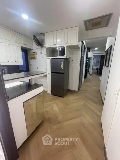 Modern kitchen with sleek design and stainless steel fridge in a contemporary apartment.