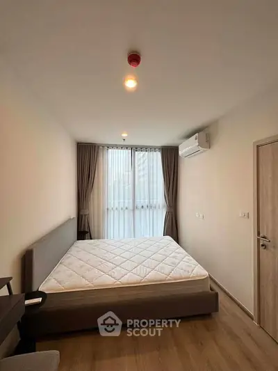 Modern bedroom with large window, air conditioning, and minimalist decor in a stylish apartment.