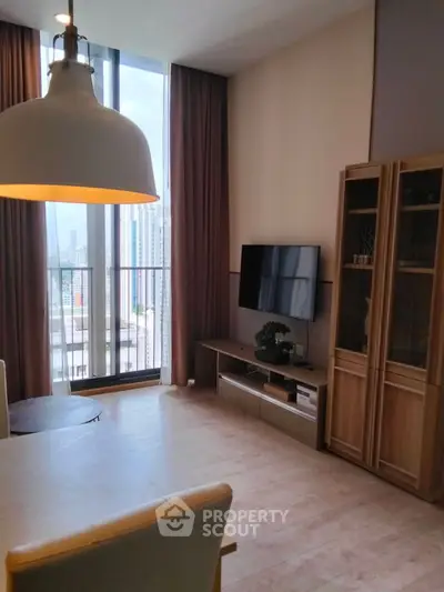 Modern living room with large windows and city view, featuring stylish furniture and decor.