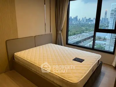 Modern bedroom with city view, featuring a comfortable bed and large window.