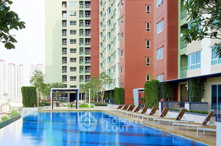 Modern apartment complex with a luxurious swimming pool and sun loungers.