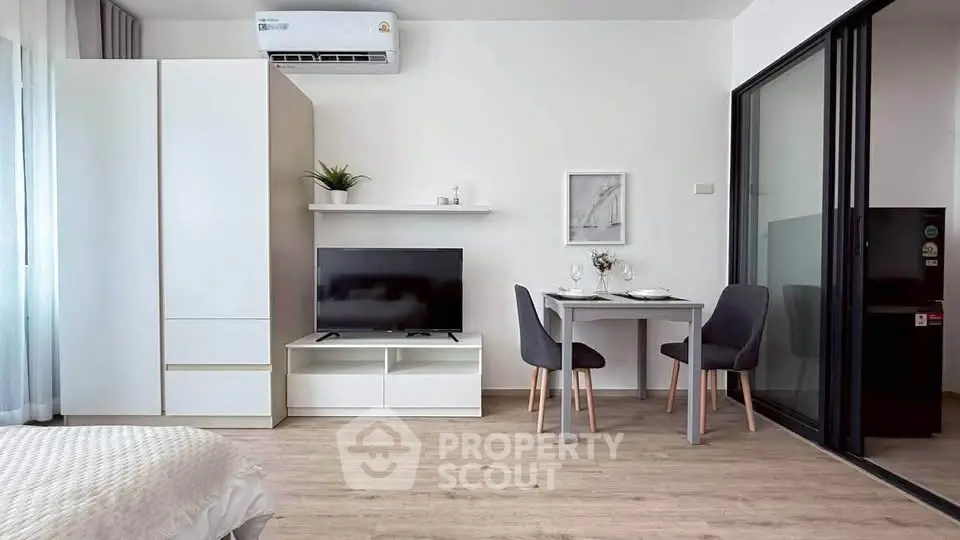 Modern studio apartment with sleek furniture and open layout, featuring a cozy dining area and stylish decor.
