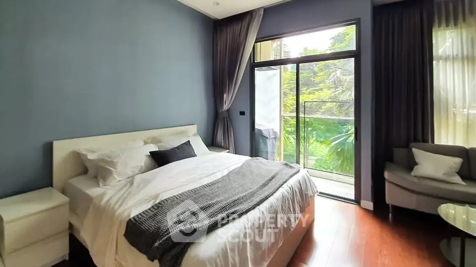 Spacious bedroom with large windows and garden view, featuring modern decor and cozy ambiance.