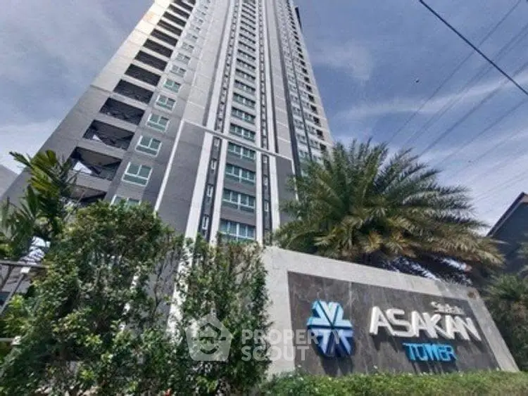 Modern high-rise building with lush greenery at Asakan Tower entrance.