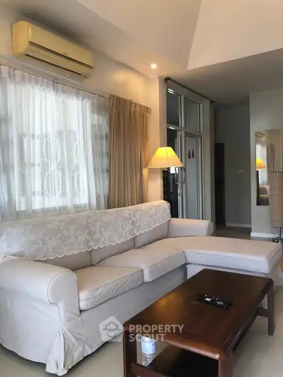 Cozy living room with sectional sofa and air conditioning, perfect for relaxation.