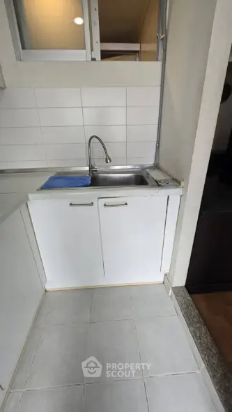 Compact kitchen area with white cabinets and stainless steel sink