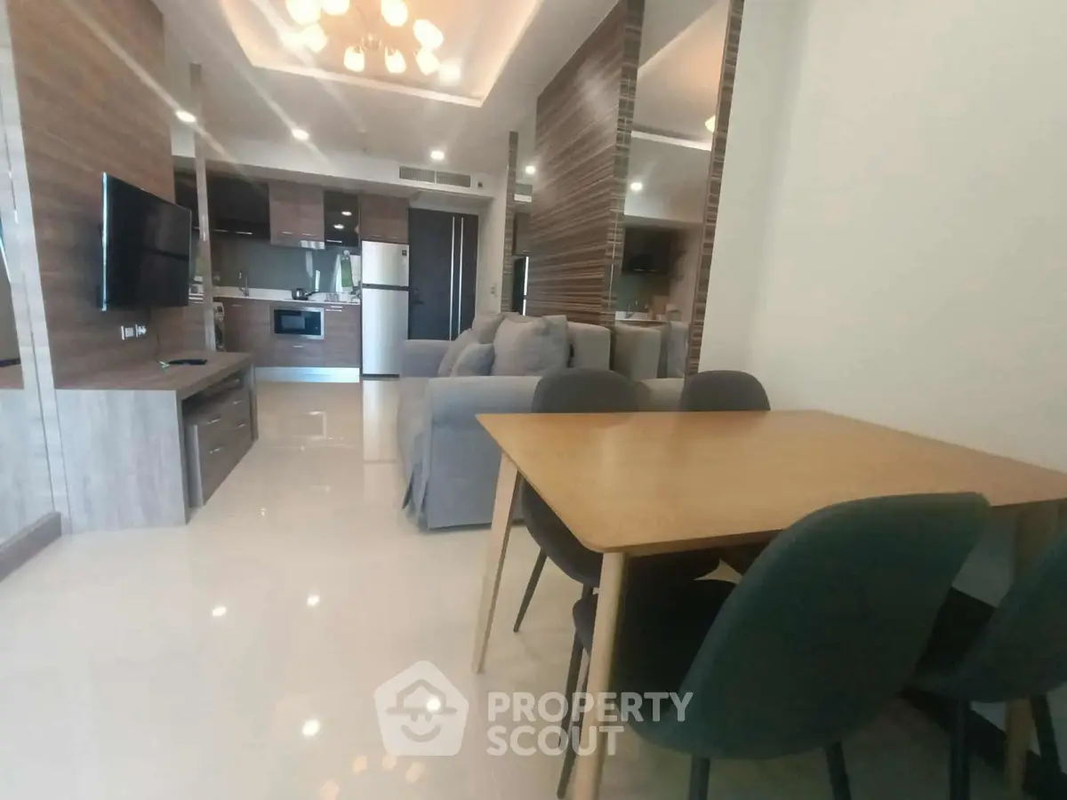 Modern open-plan living room with sleek kitchen and dining area, featuring contemporary furniture and stylish decor.