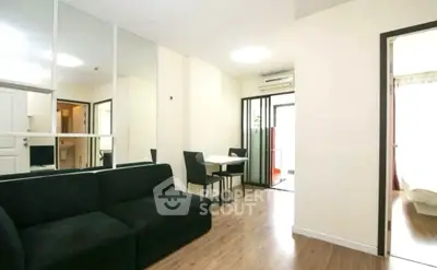 Modern living room with sleek black sofa and dining area in open layout apartment.
