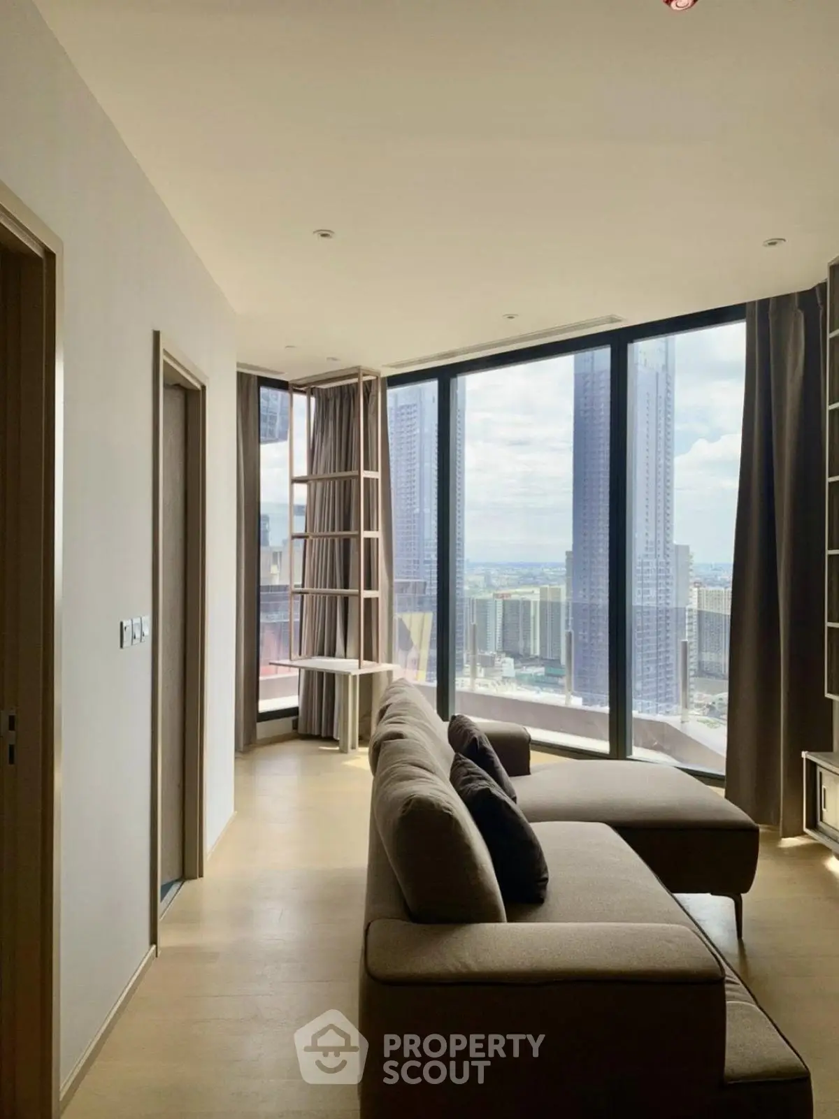 Luxurious living room with floor-to-ceiling windows offering stunning city views in a modern high-rise apartment.