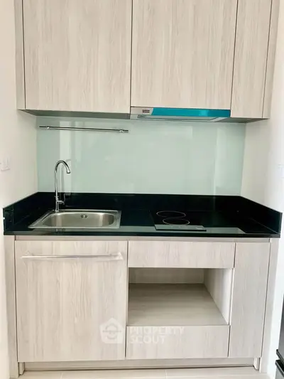 Modern compact kitchen with sleek cabinetry and electric cooktop