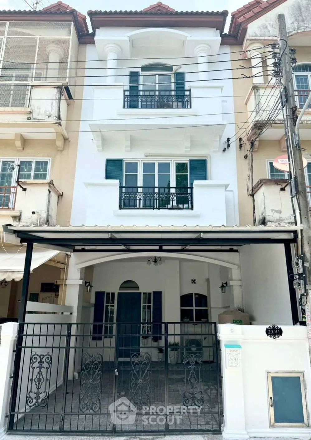Charming three-story townhouse with elegant balcony and gated entrance in a vibrant neighborhood.