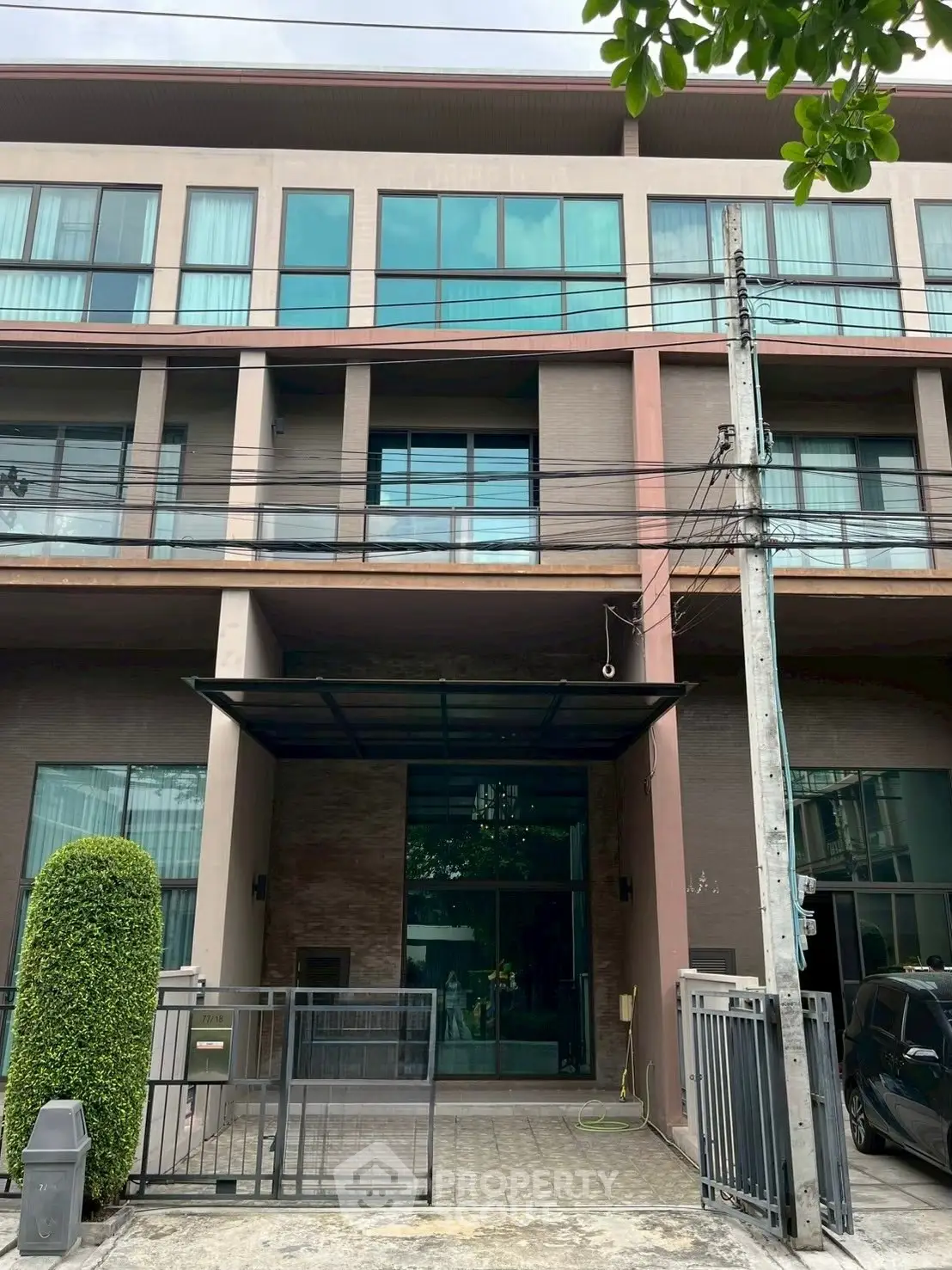 Modern townhouse exterior with large windows and gated entrance in urban setting.