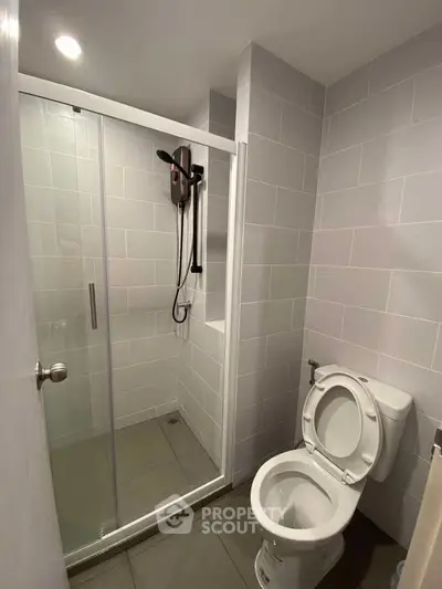 Modern bathroom with sleek shower and toilet in minimalist design.