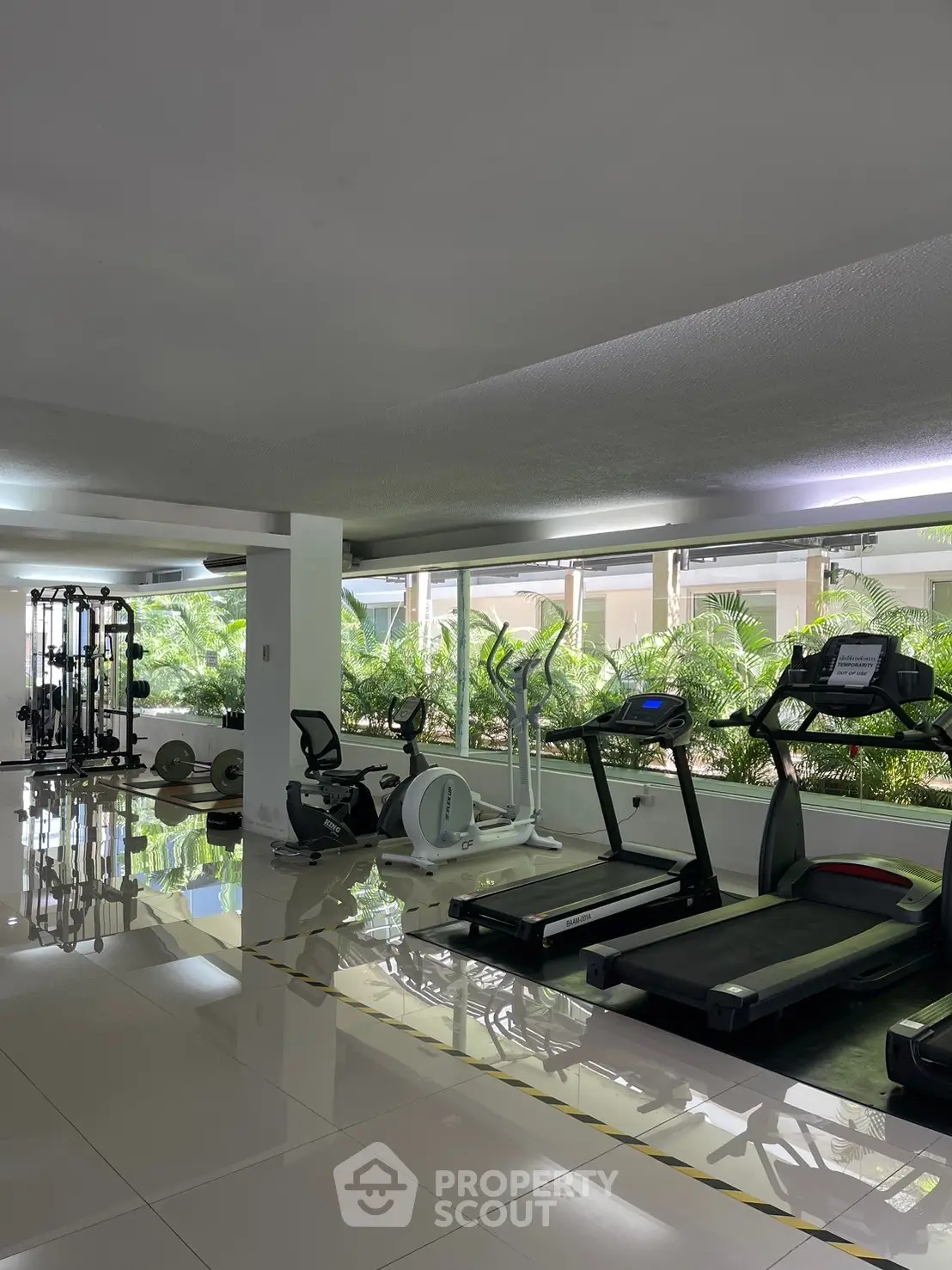 Modern gym with state-of-the-art equipment and lush greenery view.