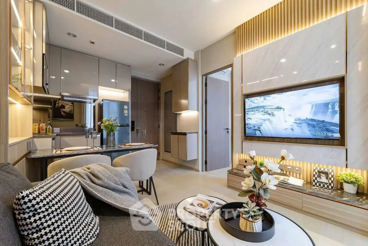 Modern living room with open kitchen, stylish decor, and wall-mounted TV in a contemporary apartment.