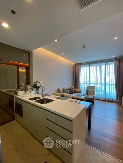 Modern open-layout kitchen and living room with elegant decor and natural light.