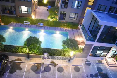 Modern apartment complex with illuminated pool and parking area at night