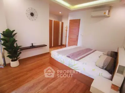 Spacious modern bedroom with wooden flooring and stylish decor