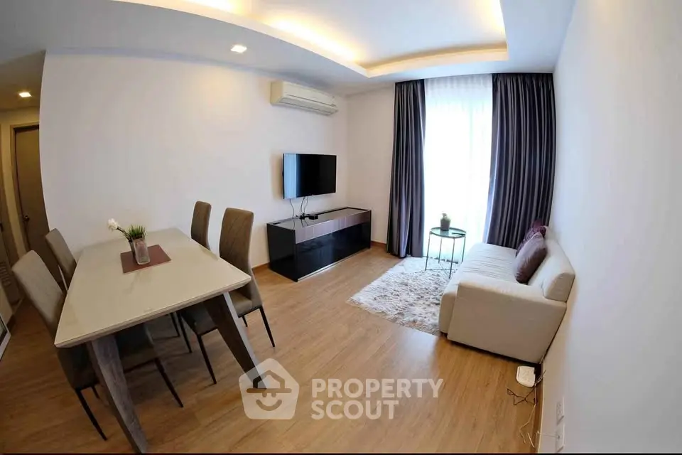 Modern living room with dining area, sleek furniture, and natural light from large window.