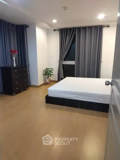 Spacious bedroom with modern decor and large window for natural light.