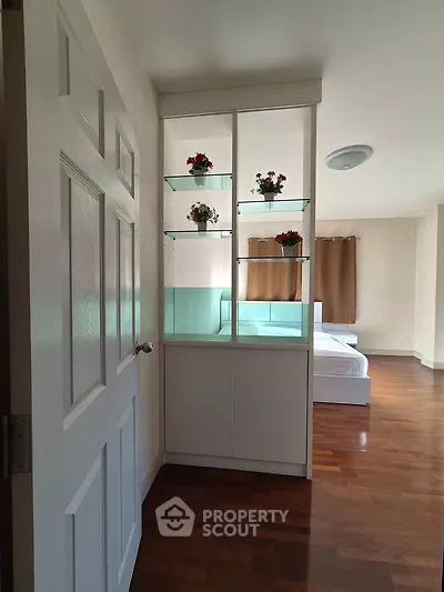 Spacious bedroom with elegant wooden flooring and decorative shelving