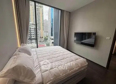 Modern bedroom with city view, featuring a sleek wall-mounted TV and large window.