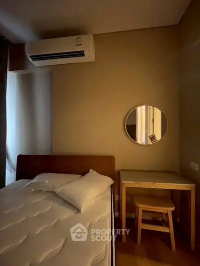 Cozy bedroom with air conditioning and minimalist decor, featuring a comfortable bed and a small desk with a mirror.