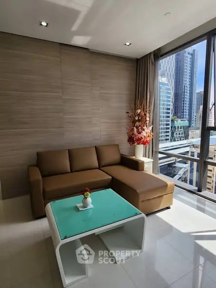 Modern living room with city view, featuring a stylish brown sofa and glass coffee table.