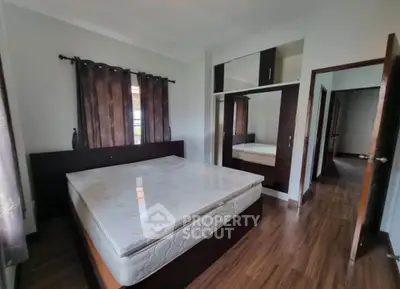 Spacious bedroom with wooden flooring and large wardrobe