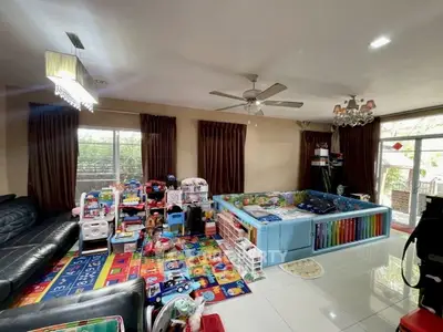 Spacious living room with play area, ceiling fan, and large windows for natural light.