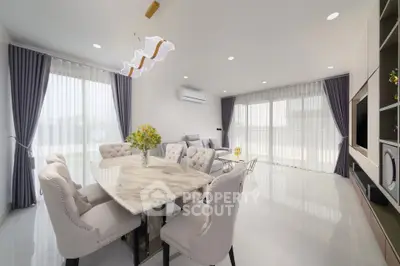 Elegant modern living room with dining area, featuring chic furniture and abundant natural light.