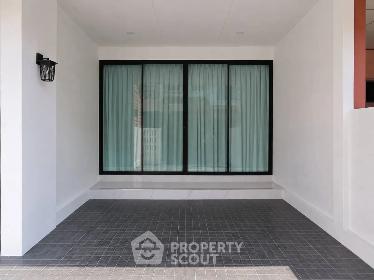 Modern minimalist exterior with large sliding glass doors and tiled patio area.