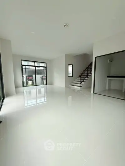 Spacious modern living room with sleek staircase and large windows for natural light.