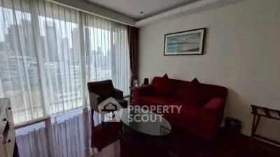 Modern living room with city view, featuring elegant furniture and floor-to-ceiling windows.