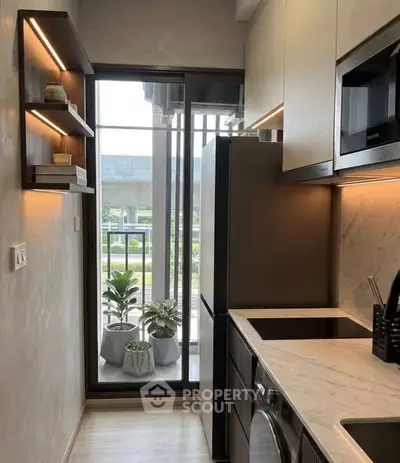 Modern kitchen with sleek appliances and balcony view, featuring a compact yet stylish design.