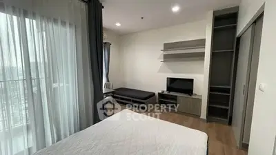 Modern bedroom with balcony view, sleek furniture, and ample natural light.