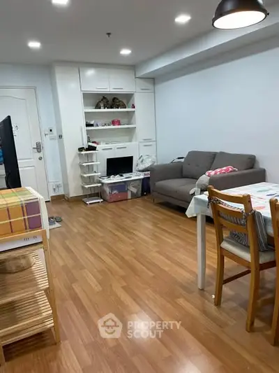 Cozy living room with wooden flooring, modern sofa, and dining area in a stylish apartment.