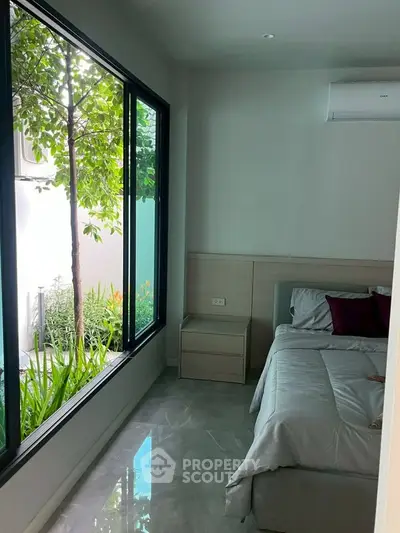 Modern bedroom with large window and garden view, featuring sleek design and natural light.