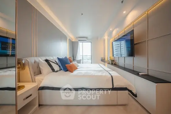 Luxurious modern bedroom with sleek design and large TV, perfect for relaxation.