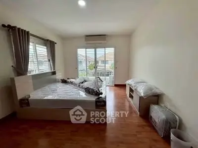 Spacious bedroom with large windows and wooden flooring in a modern home.