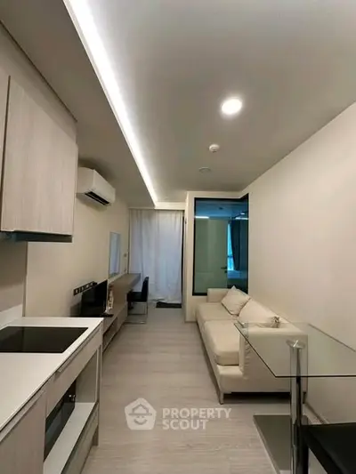 Modern living room with sleek design and open layout, featuring a cozy sofa and stylish kitchen area.