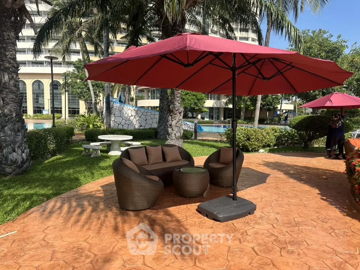 Luxurious outdoor seating area with umbrella by the poolside in a tropical garden setting.