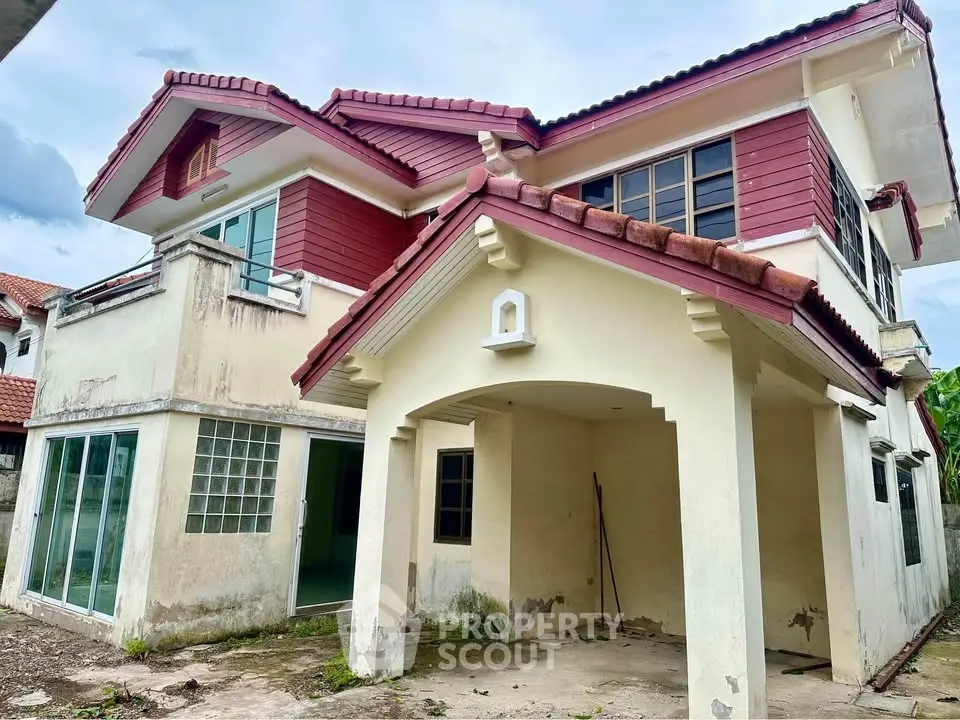 Charming two-story house with red roof and spacious carport, ideal for family living.