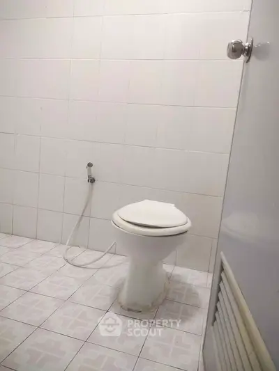 Simple bathroom with white tiles and toilet in real estate property.